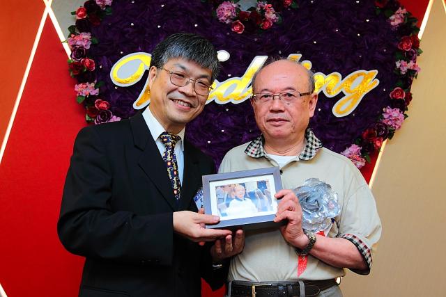 古博仁理事長精心製作去年度敬老聯誼餐會出席藥師的照片相框並贈送給藥師作為紀念（圖中為藍炳煌顧問）